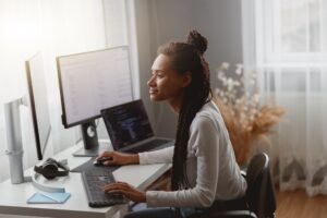 Side view of mixed-race young professional concentrated skilled web expert working on computer